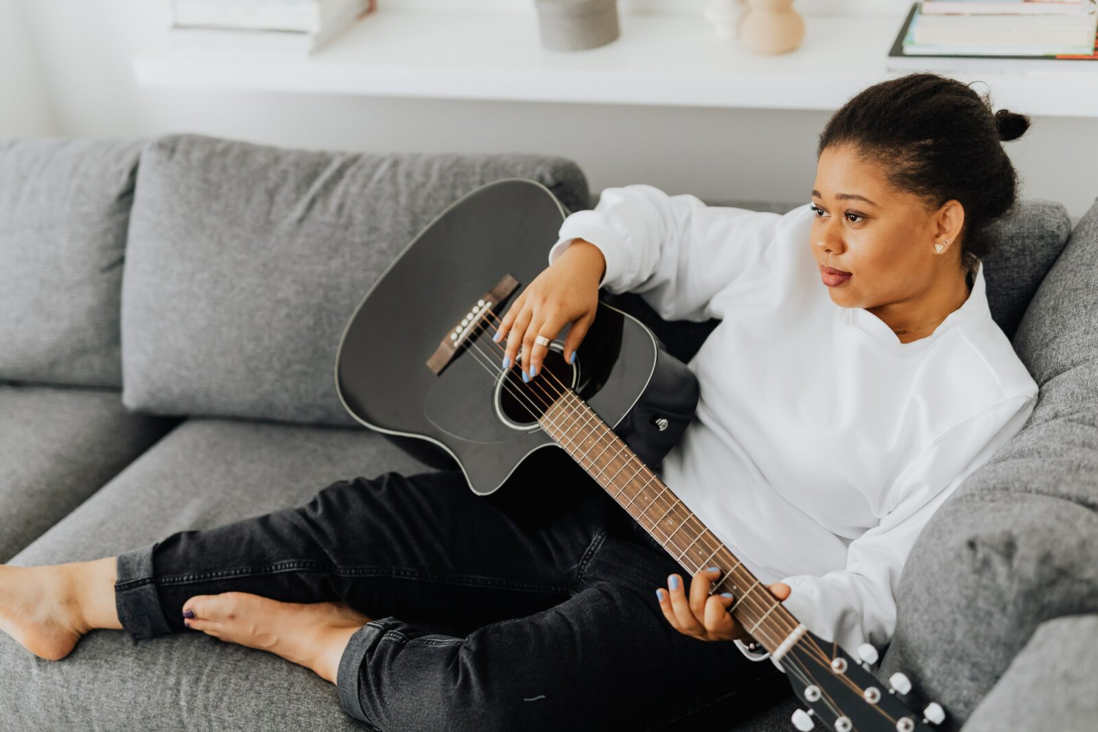 woman sitting on couch playing guitar